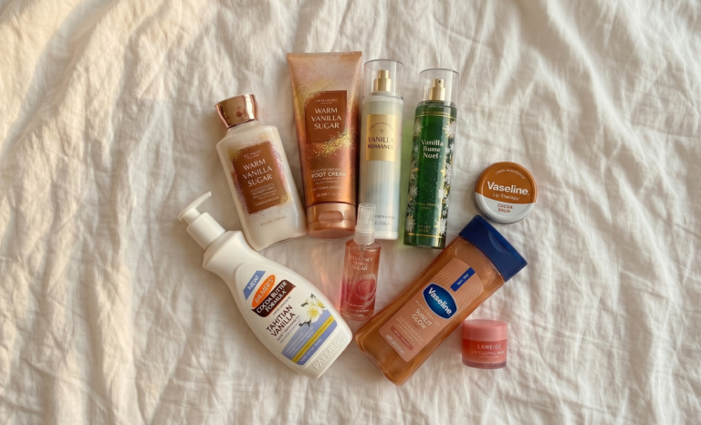 "Vanilla-themed beauty and skincare product collection. Features moisturizing lotions, body oils, and perfume mists by Vaseline, Palmer's, and Bath & Body Works on a white fabric background with soft natural lighting."